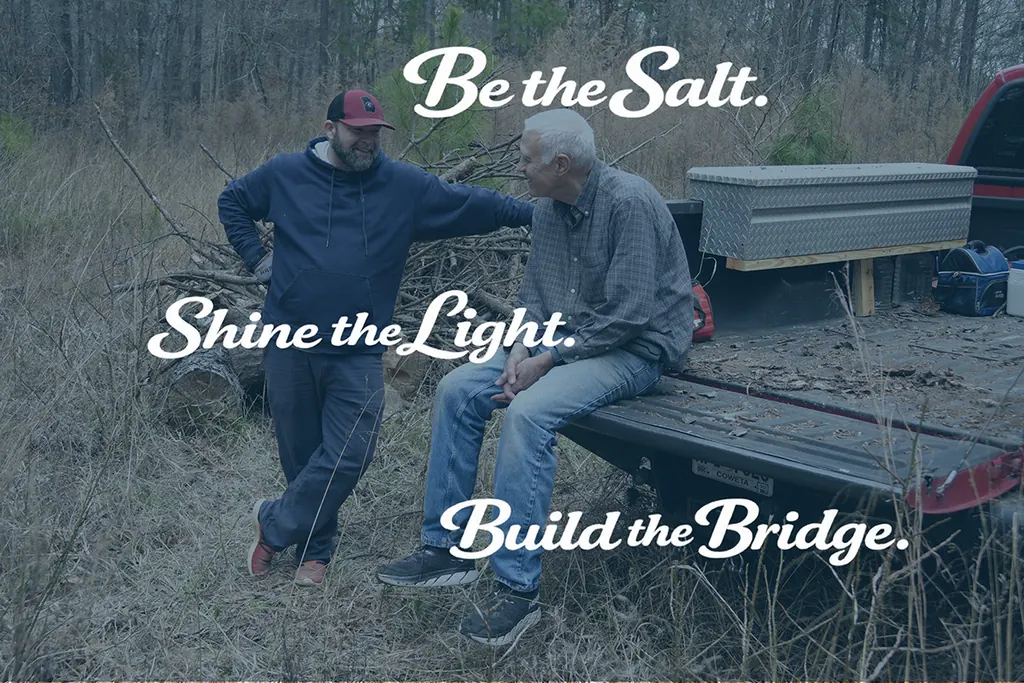 A Salt Light Bridge volunteer and a Neighbor laughing together beside a truck