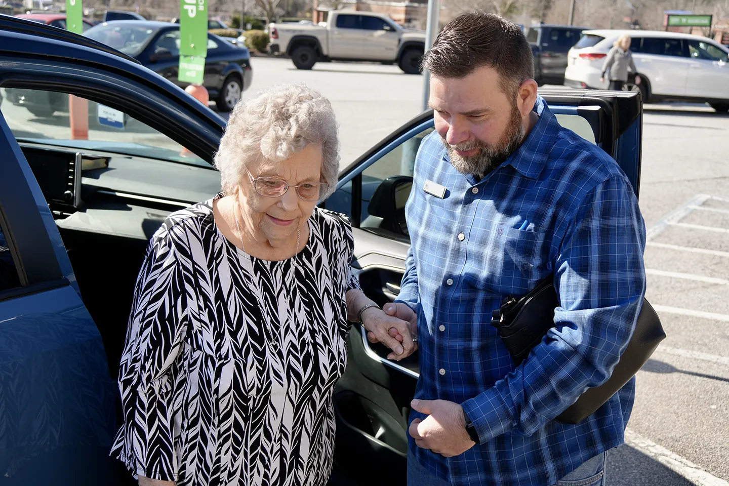 A volunteer holding a Neighbor’s hand as she steps out of a car