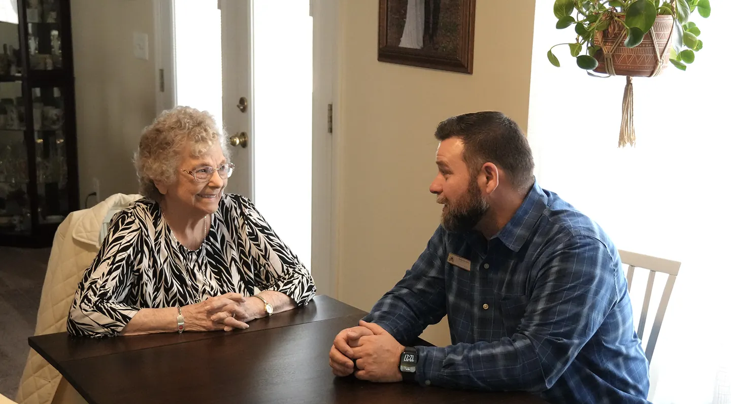 A volunteer and a Neighbor talking together at a kitchen table